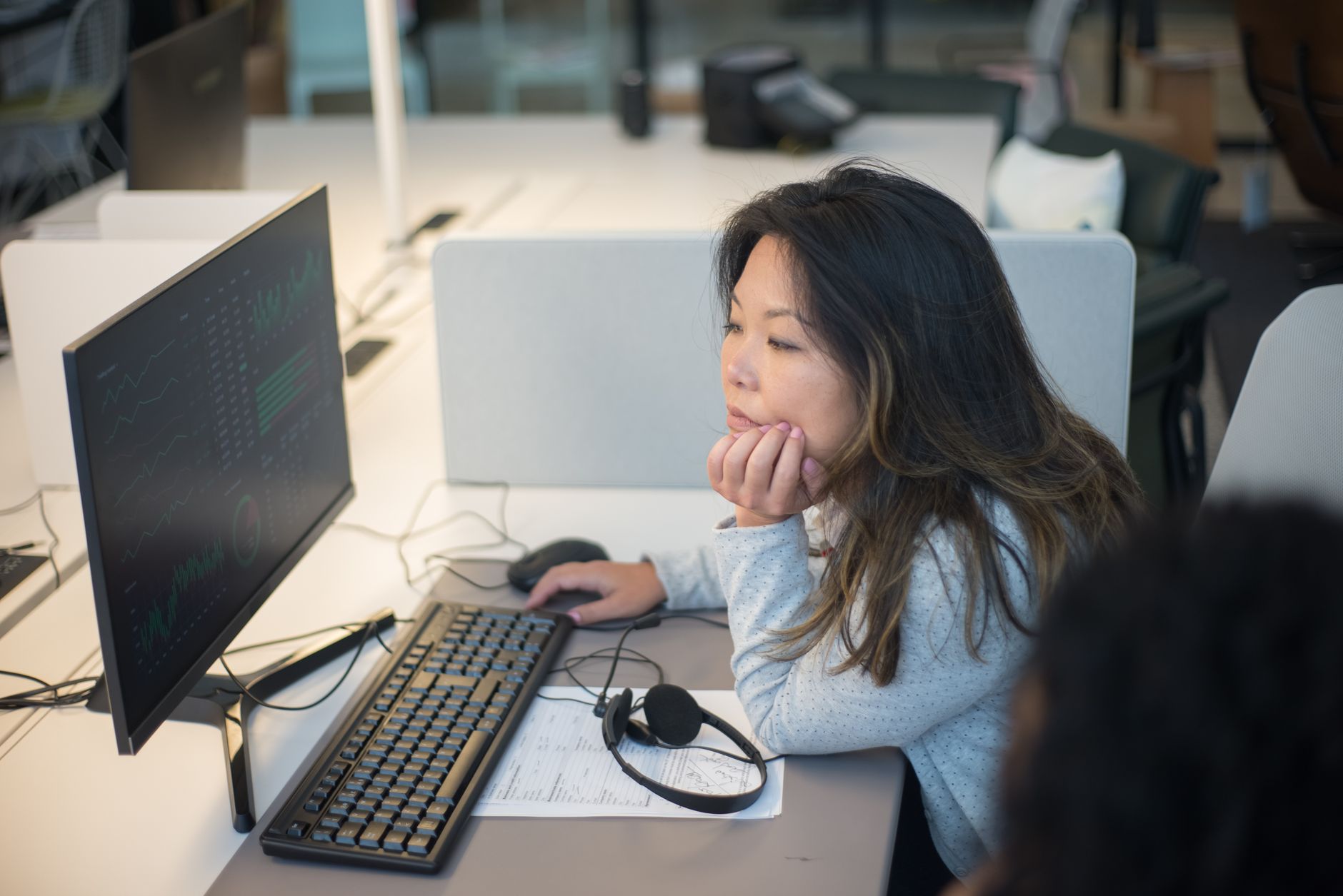 Woman intently viewing a computer monitor in a modern office environment.