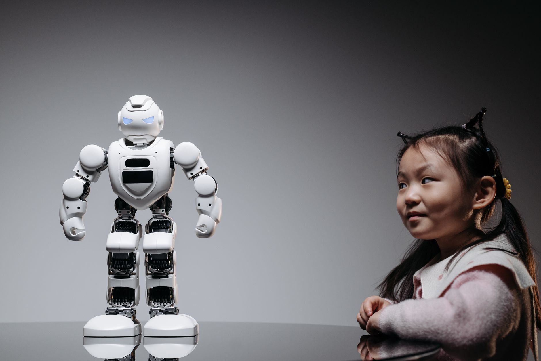 Young Asian girl interacts with a high-tech toy robot, showcasing innovation and curiosity.