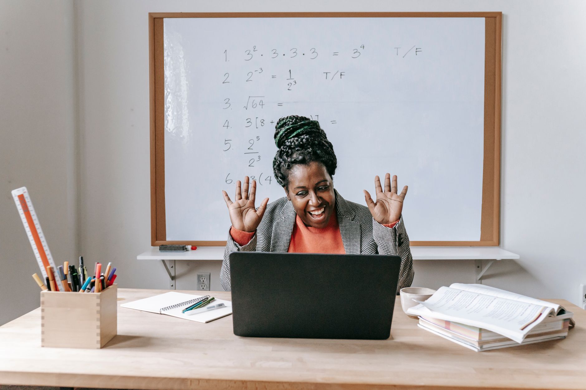 Cheerful African American female teaching online lesson with netbook in modern classroom