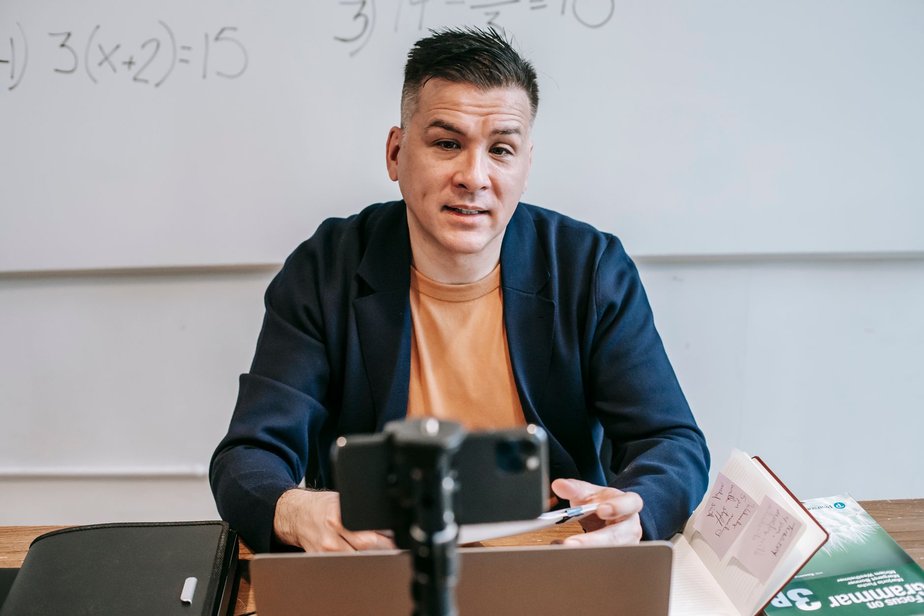 A professional educator conducting an online class, engaging with students via video call.