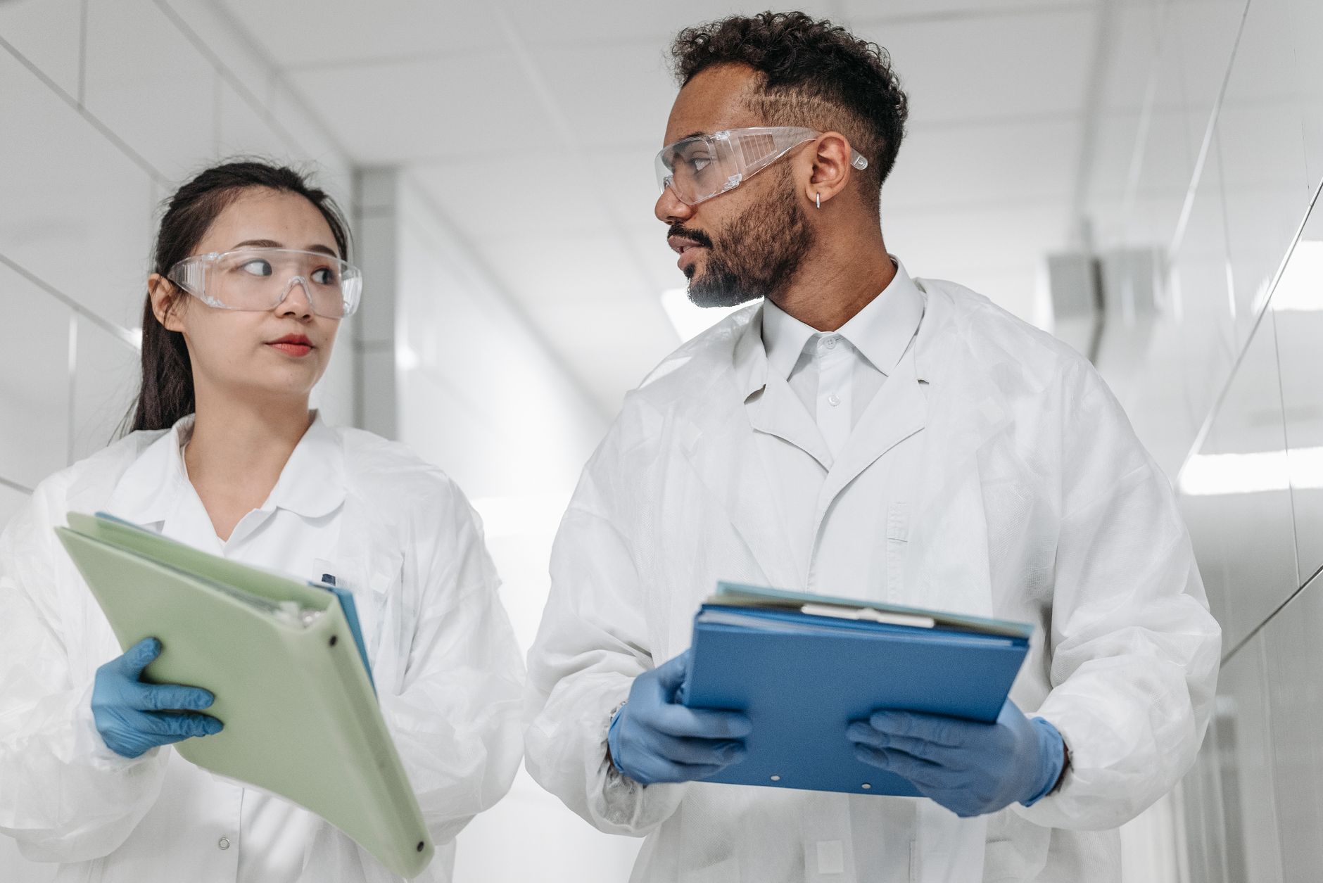 Two scientists in protective gear discuss research in a laboratory setting, focused on collaboration and safety.