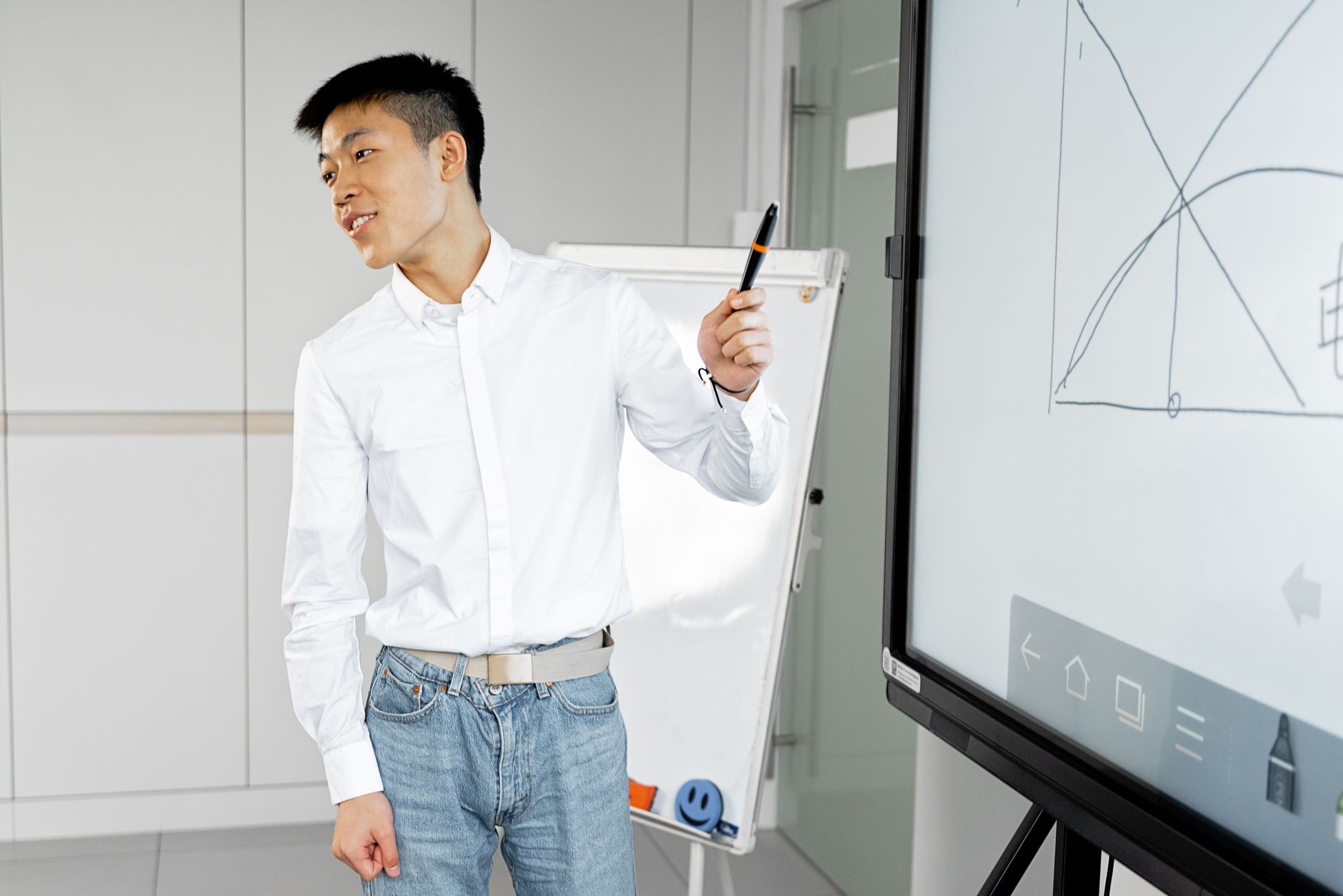 Asian man presenting with smart board in a modern office setting.