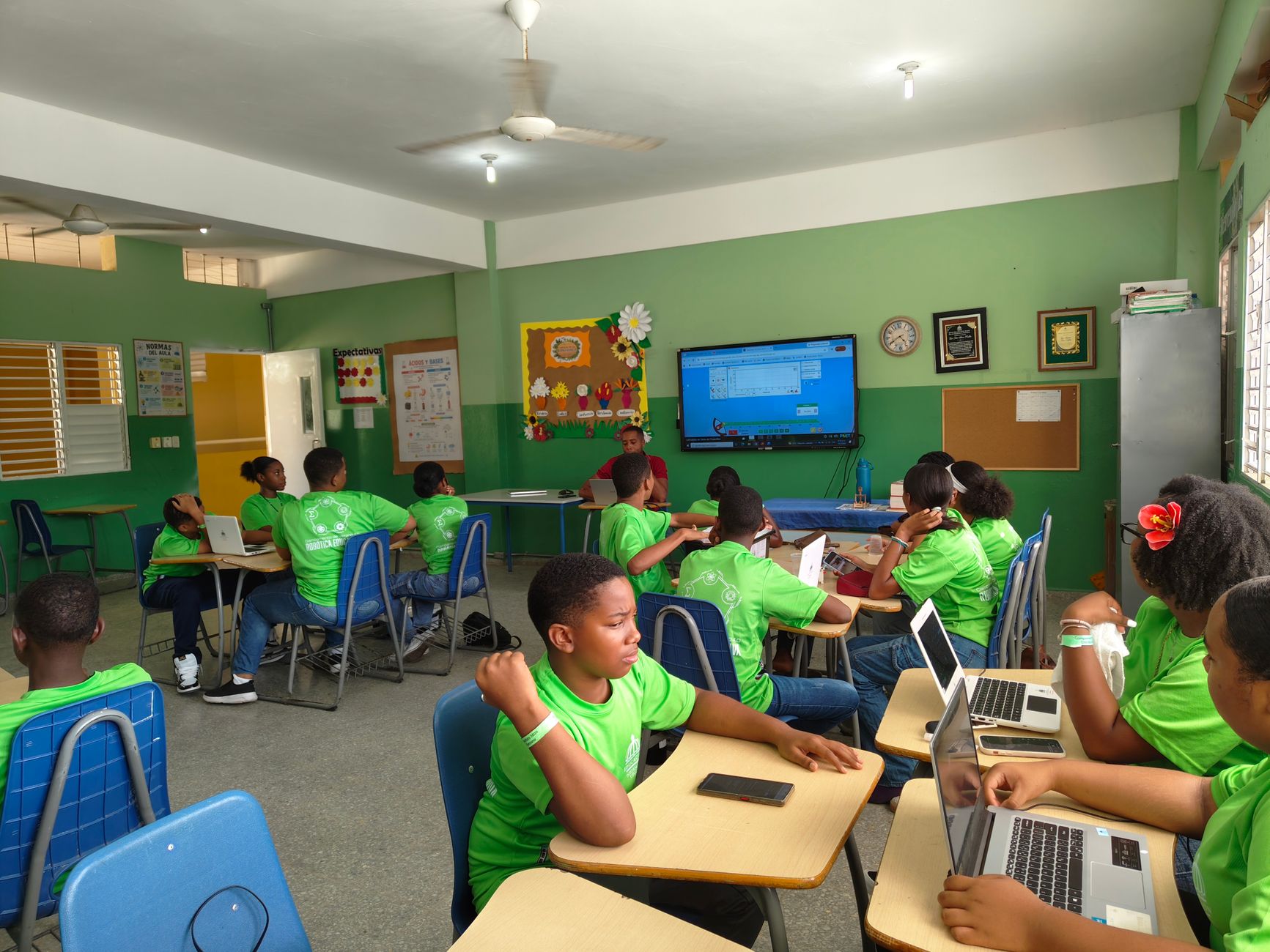 Group of students in a classroom using laptops and participating in a lesson.