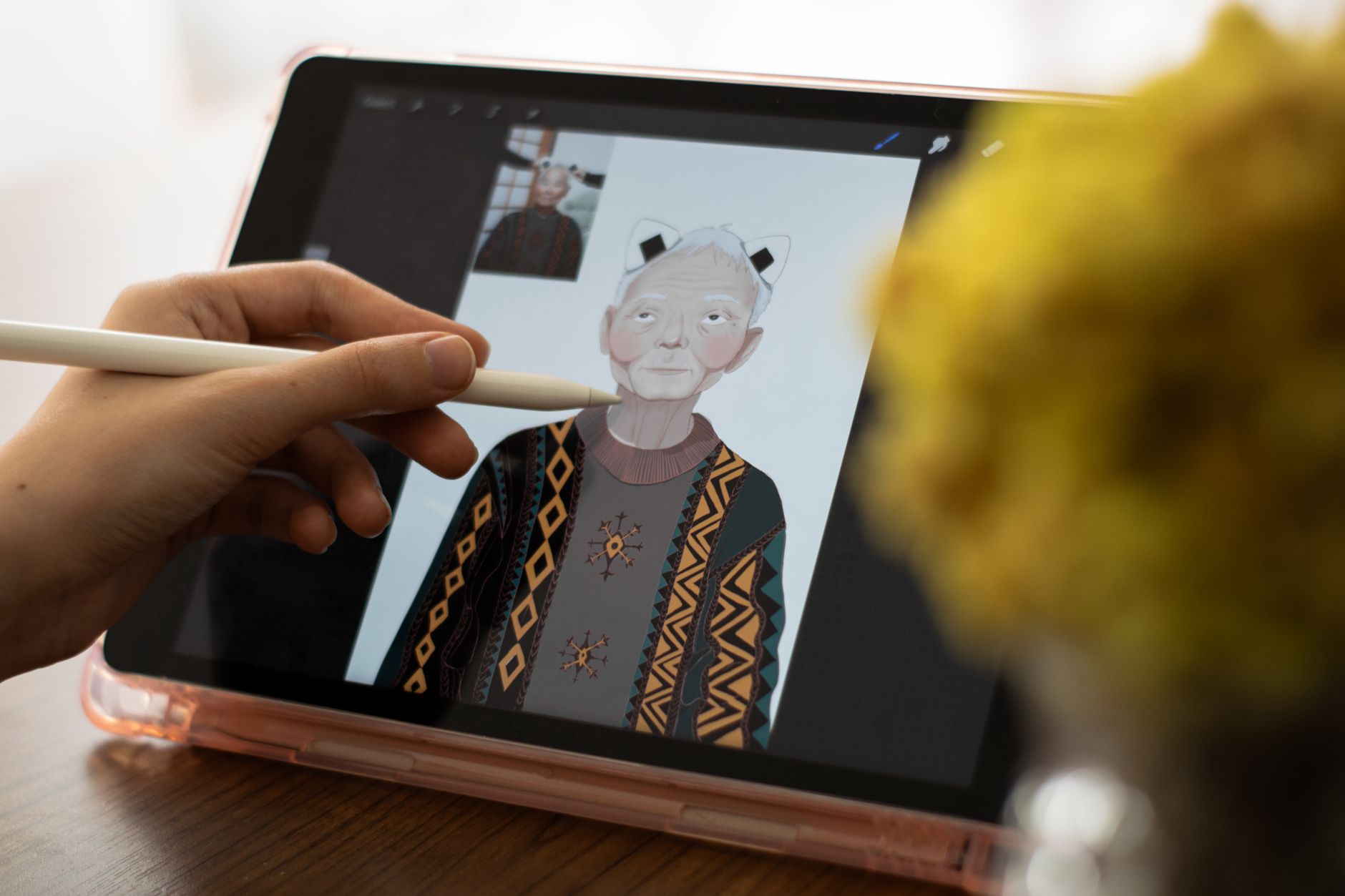 Close-up of hands using a tablet and stylus for digital art creation, depicting an elderly character.