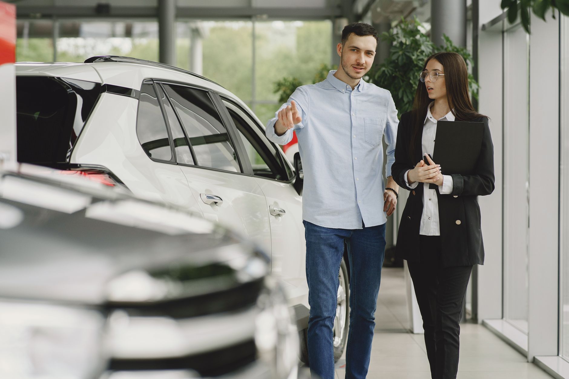 Customer and salesperson discussing a vehicle inside a modern car dealership showroom.