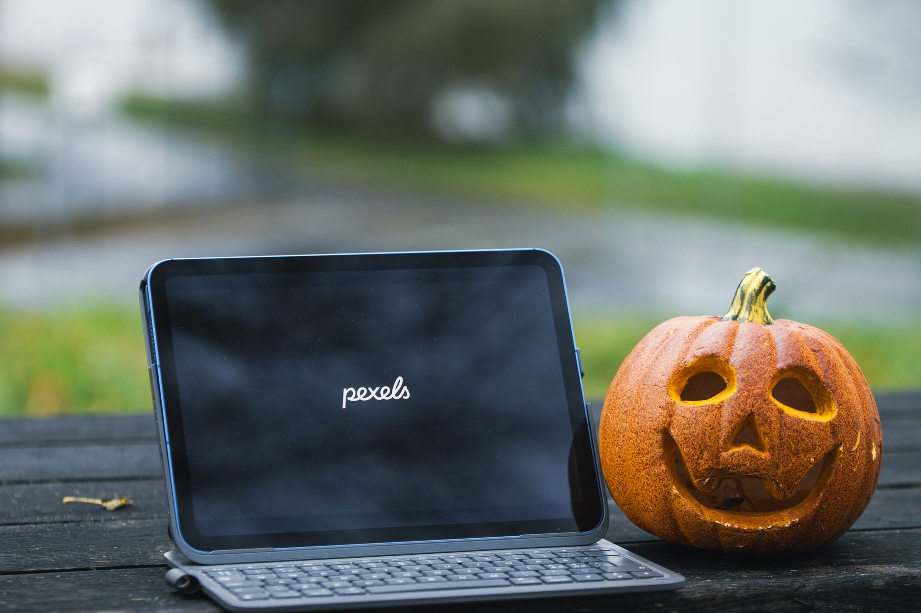 A tablet next to a carved pumpkin outdoors in Jönköping, Sweden, during the fall.